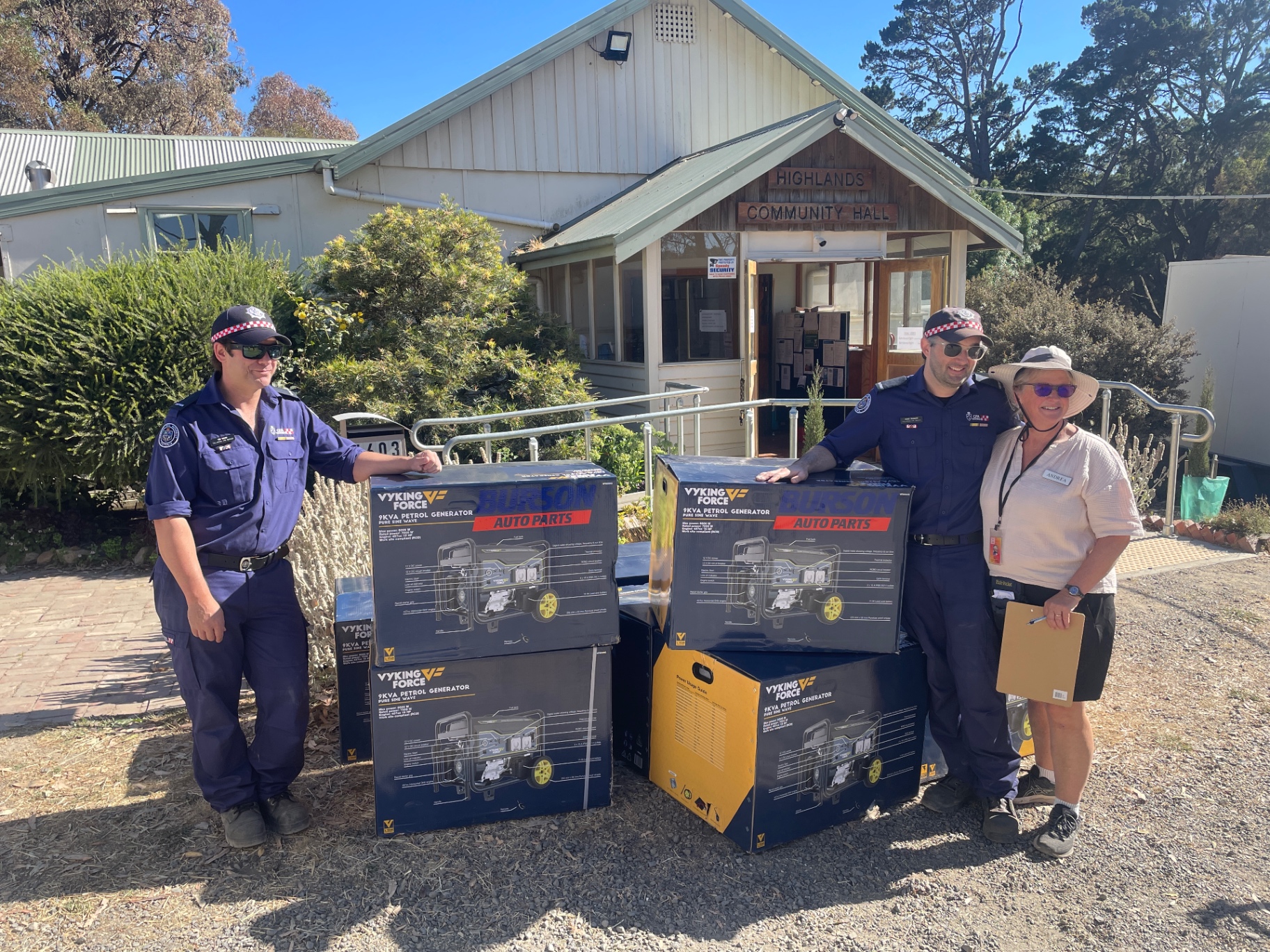Emergency services members and a volunteer with donated petrol generators outside the hall