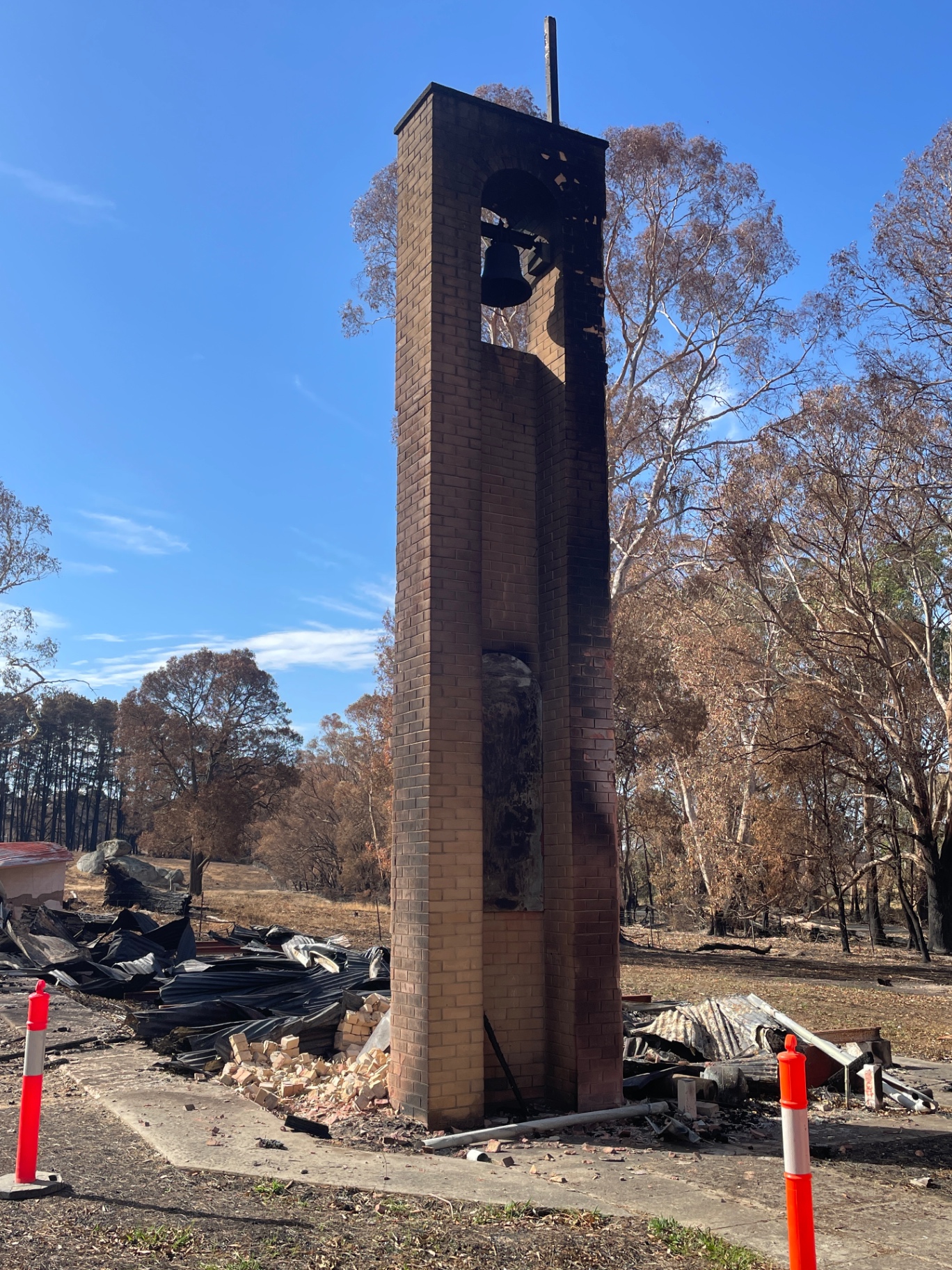 A brick bell tower left standing among the ruins of a burnt building