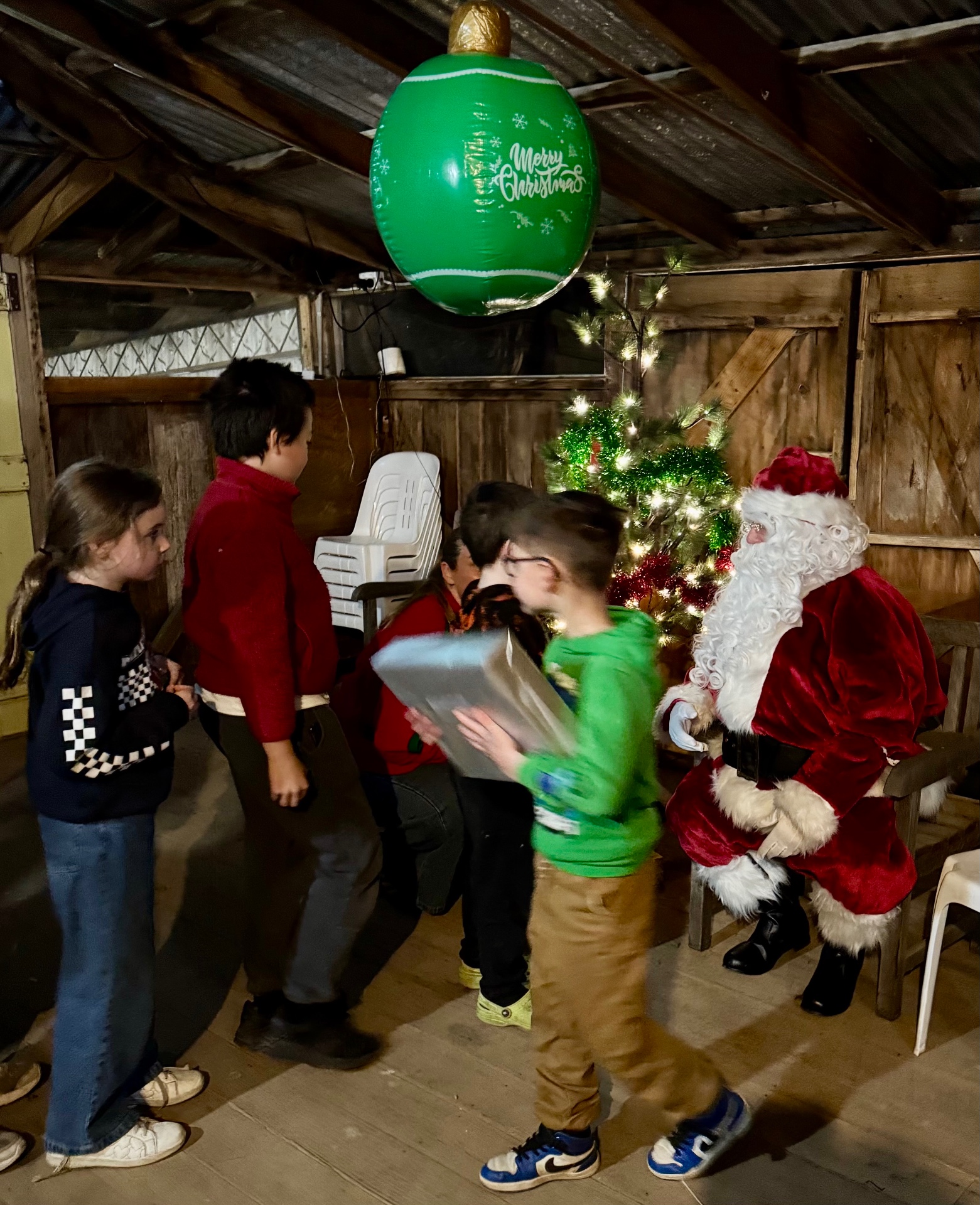 Children lining up to collect presents from Santa in the shed