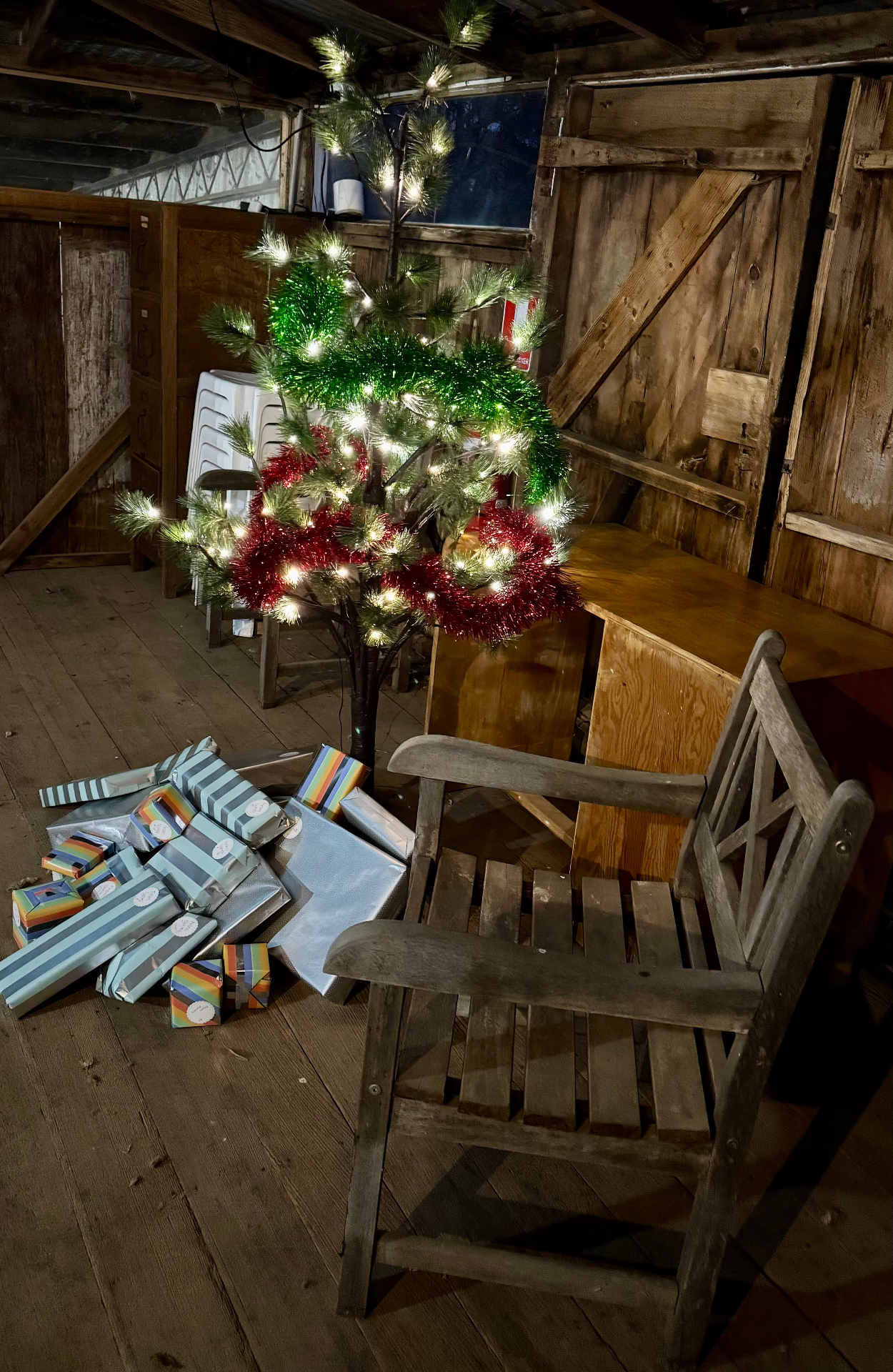 A lit Christmas tree and wrapped presents inside the shearing shed