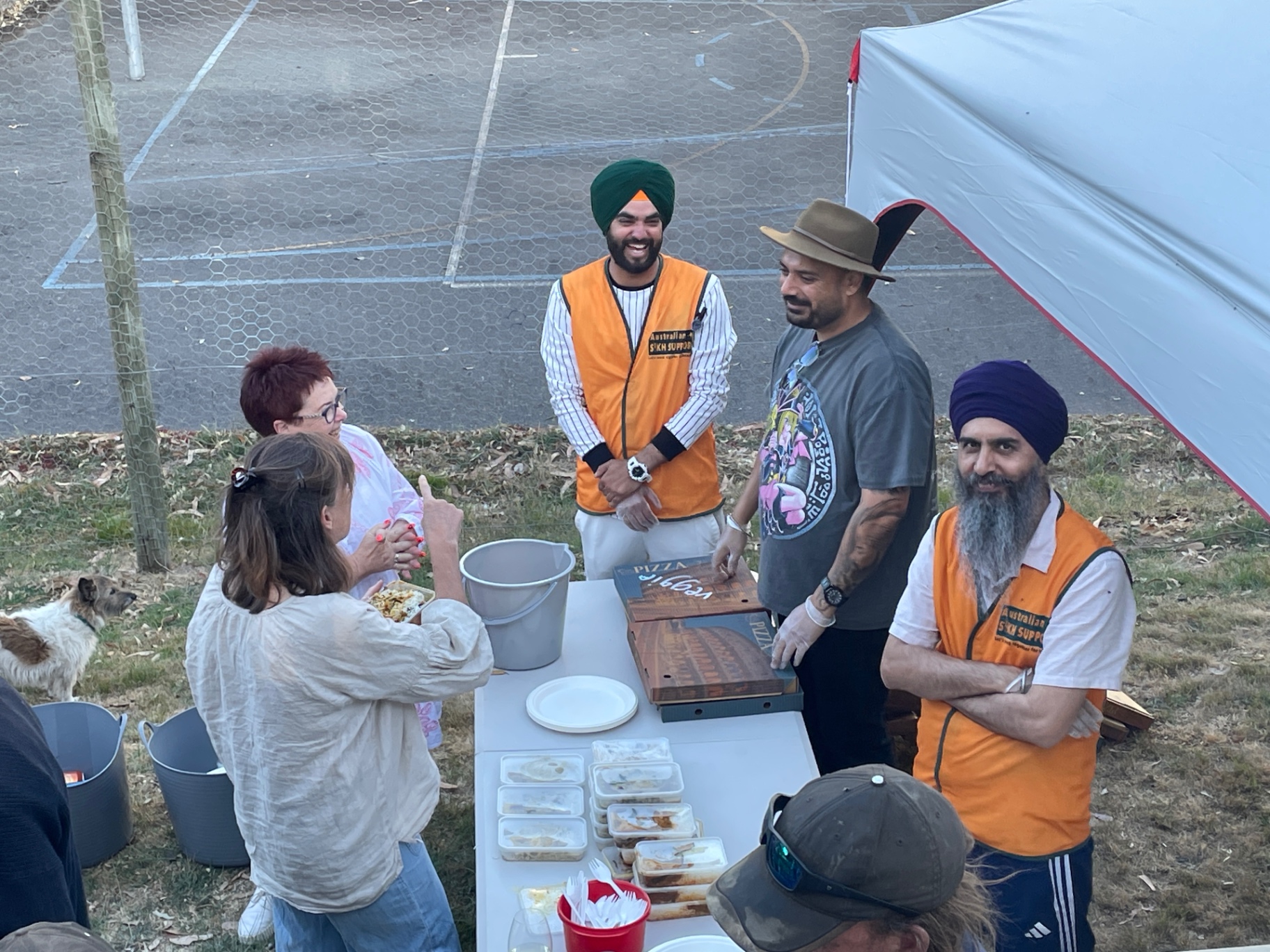 Australian Sikh Support volunteers serving hot meals to locals under a marquee