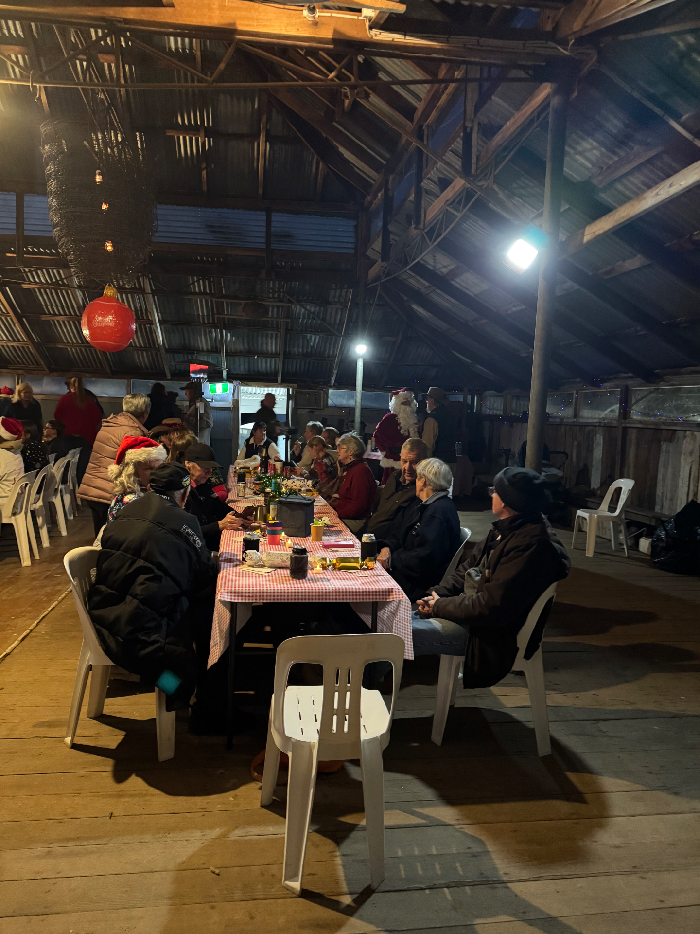 Locals seated at long trestle tables under the shearing shed roof